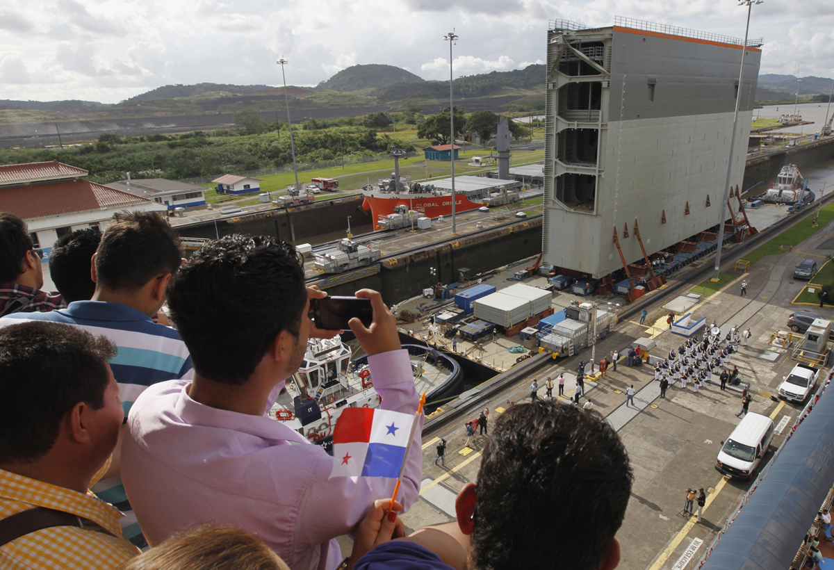 Люди фотографируют буксировку стальных ворот для шлюза, Панама-Сити, 10 декабря 2014 года.